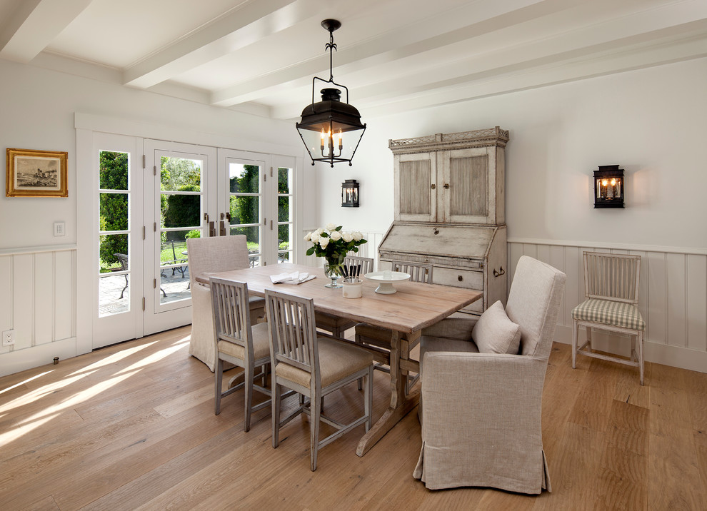 This is an example of a country separate dining room in Santa Barbara with white walls and light hardwood floors.
