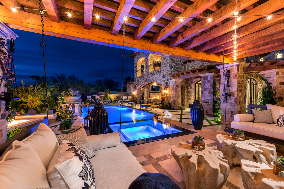Inspiration for an expansive country backyard patio in Phoenix with a fire feature, natural stone pavers and a roof extension.