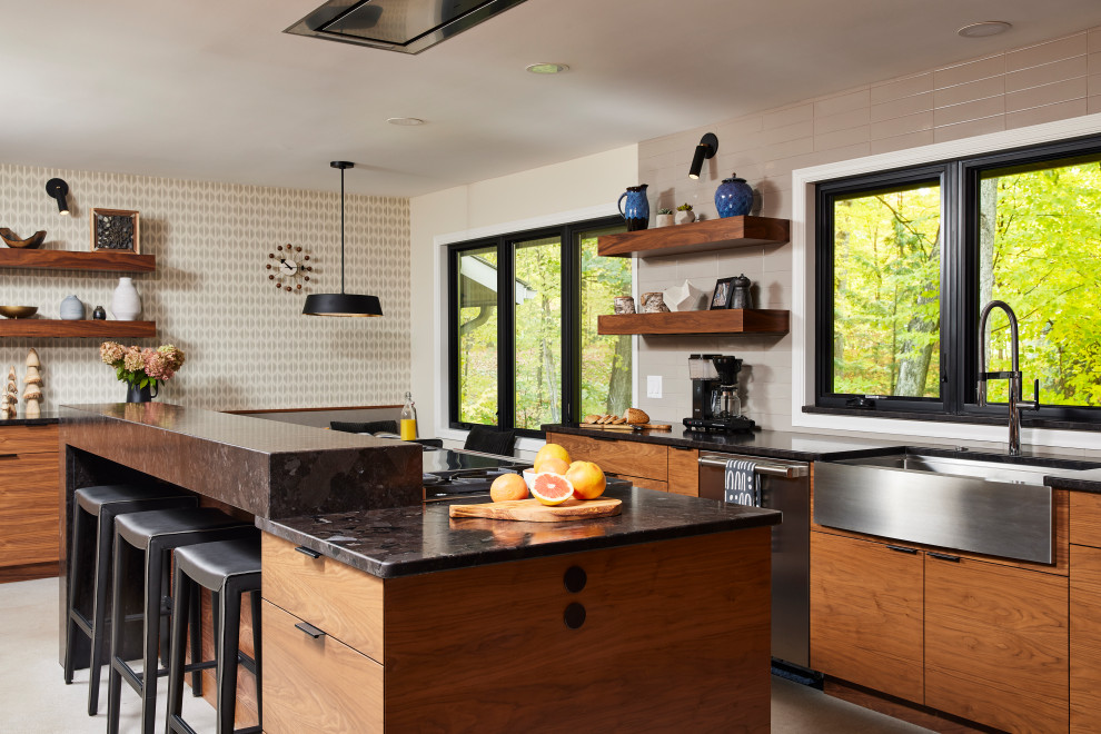 Inspiration for a large transitional u-shaped porcelain tile and gray floor enclosed kitchen remodel in Minneapolis with a farmhouse sink, flat-panel cabinets, medium tone wood cabinets, granite countertops, gray backsplash, ceramic backsplash, stainless steel appliances, an island and black countertops