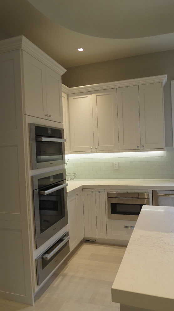 Inspiration for a large transitional l-shaped light wood floor and beige floor enclosed kitchen remodel in Miami with a double-bowl sink, shaker cabinets, white cabinets, marble countertops, blue backsplash, glass tile backsplash, stainless steel appliances and an island
