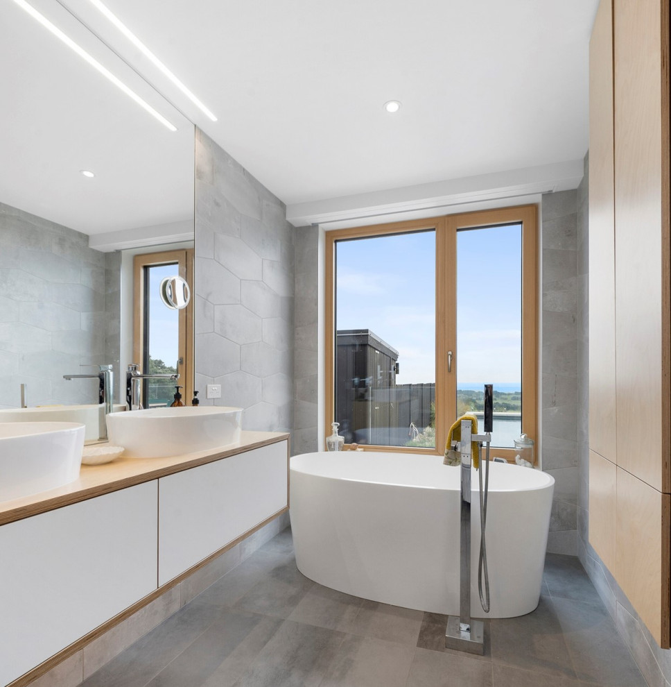 This is an example of a large contemporary ensuite bathroom in Other with white cabinets, a freestanding bath, grey tiles, ceramic tiles, wooden worktops, brown worktops, double sinks and a floating vanity unit.
