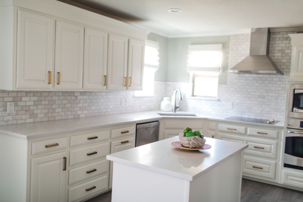 Inspiration for a mid-sized beach style u-shaped separate kitchen in Dallas with an undermount sink, raised-panel cabinets, white cabinets, solid surface benchtops, grey splashback, marble splashback, stainless steel appliances, porcelain floors, with island, grey floor and white benchtop.