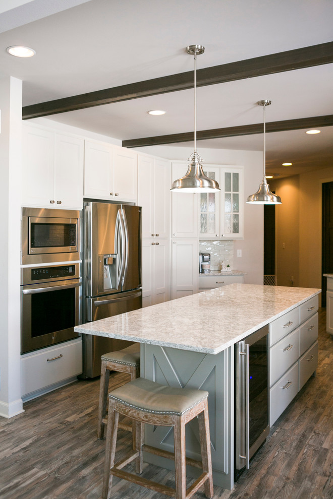Example of a mid-sized mountain style l-shaped open concept kitchen design with raised-panel cabinets, white cabinets, granite countertops, white backsplash, subway tile backsplash, stainless steel appliances, an island and gray countertops