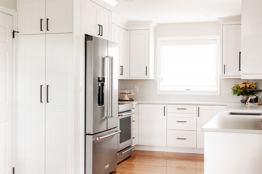 Kitchen - transitional light wood floor and brown floor kitchen idea in Toronto with an undermount sink, shaker cabinets, white cabinets, quartz countertops, white backsplash, stainless steel appliances, no island and white countertops