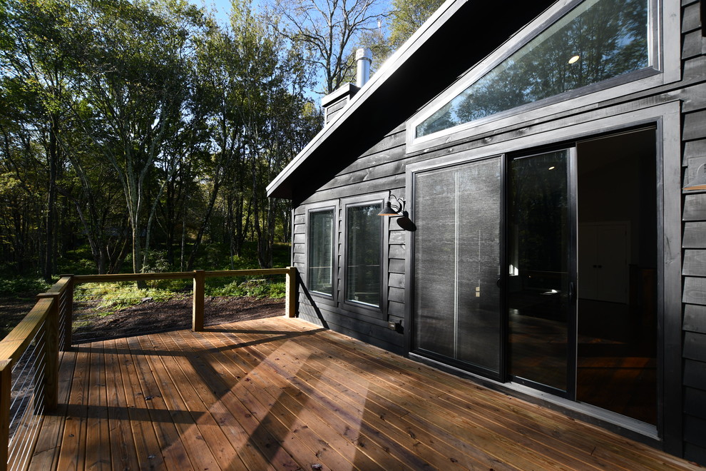 This is an example of a mid-sized midcentury backyard screened-in verandah in New York with decking and a roof extension.