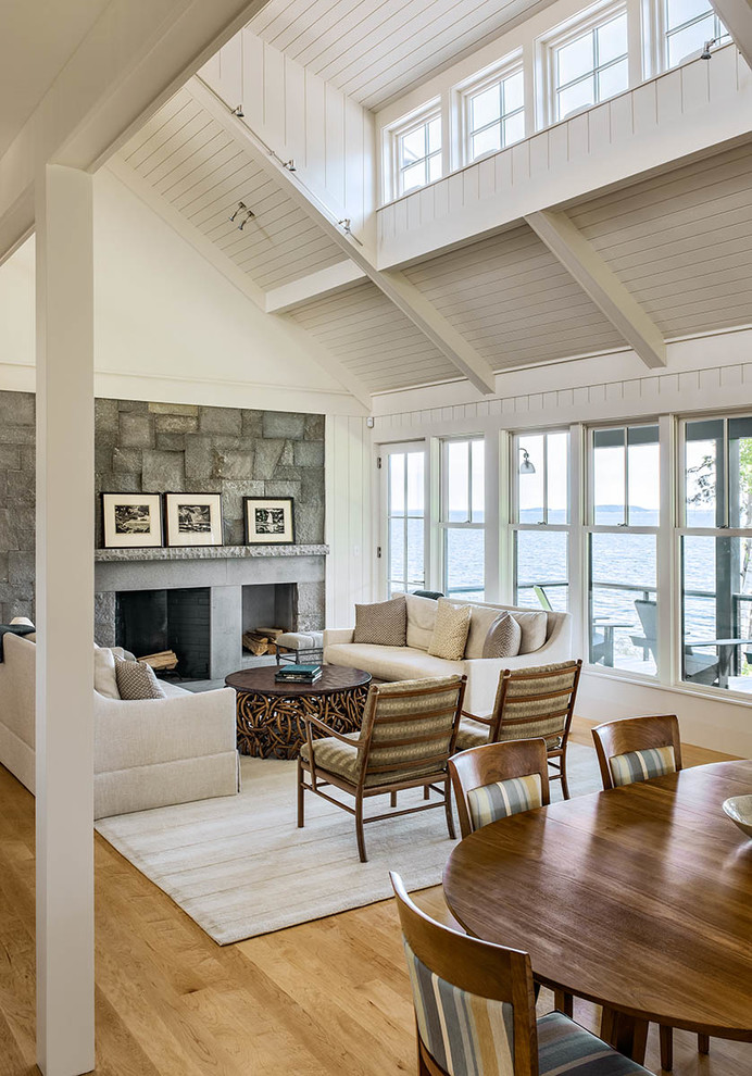 Large beach style formal open concept living room in Portland Maine with white walls, light hardwood floors, a standard fireplace and a concrete fireplace surround.