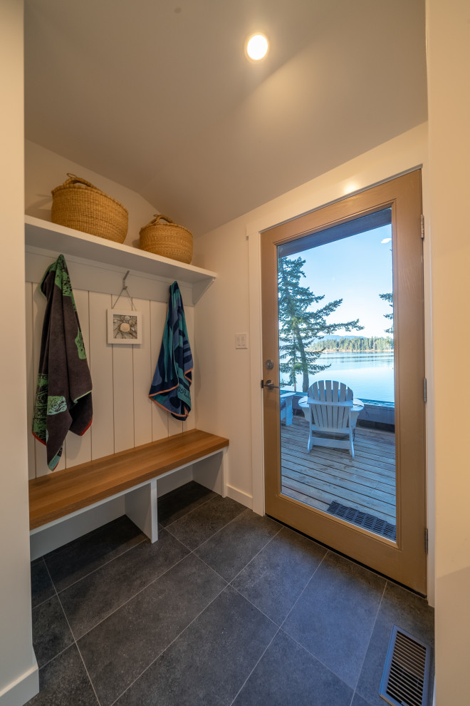 Example of a beach style galley porcelain tile and gray floor utility room design in Vancouver with a drop-in sink, white cabinets, quartz countertops, white backsplash, subway tile backsplash, white walls, a side-by-side washer/dryer and white countertops