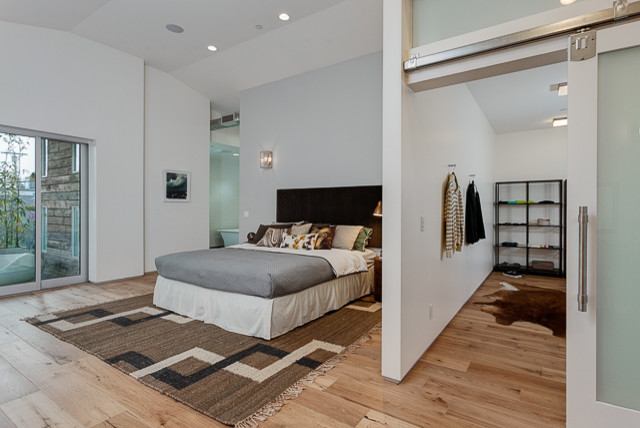 This is an example of a large contemporary master bedroom in Los Angeles with white walls and light hardwood floors.