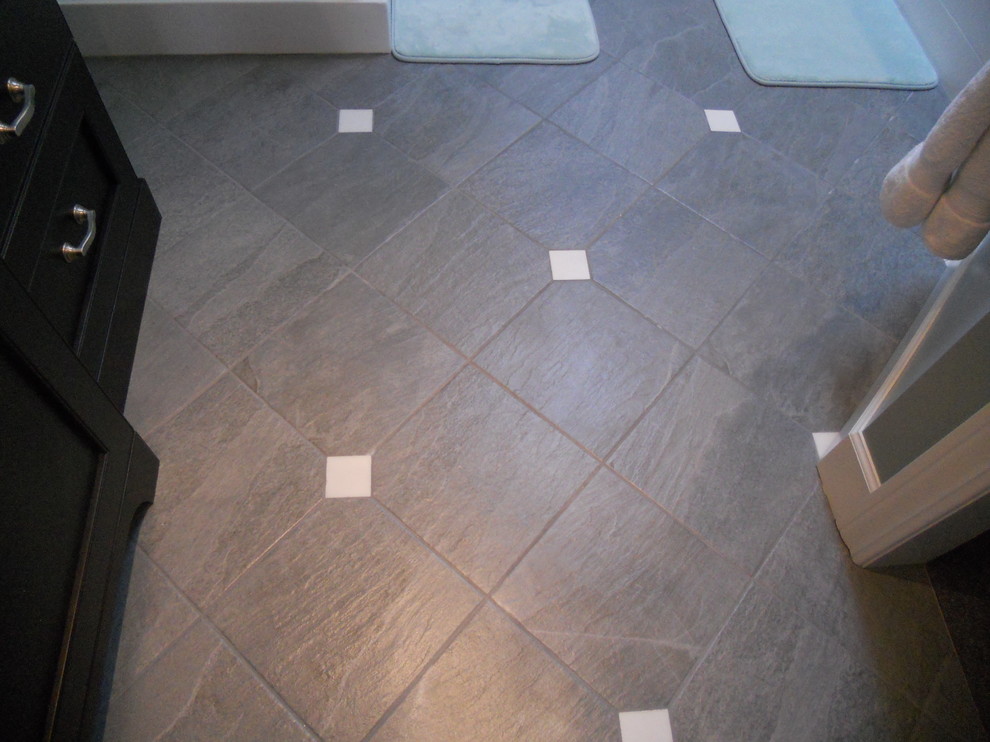 Large transitional master gray tile and stone tile ceramic tile corner bathtub photo with an undermount sink, recessed-panel cabinets, dark wood cabinets, quartz countertops, a two-piece toilet and gray walls