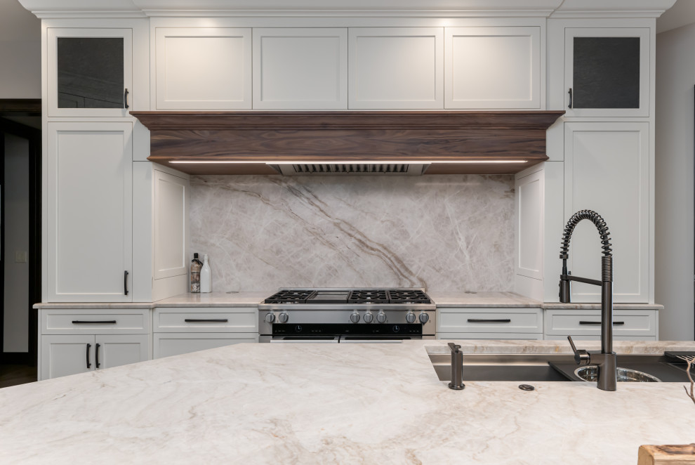 Large transitional medium tone wood floor and brown floor open concept kitchen photo with a double-bowl sink, flat-panel cabinets, white cabinets, quartzite countertops, beige backsplash, stainless steel appliances, an island and beige countertops