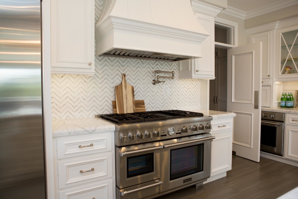 Eat-in kitchen - large transitional l-shaped porcelain tile and gray floor eat-in kitchen idea in San Diego with a farmhouse sink, raised-panel cabinets, white cabinets, marble countertops, white backsplash, marble backsplash, stainless steel appliances and an island