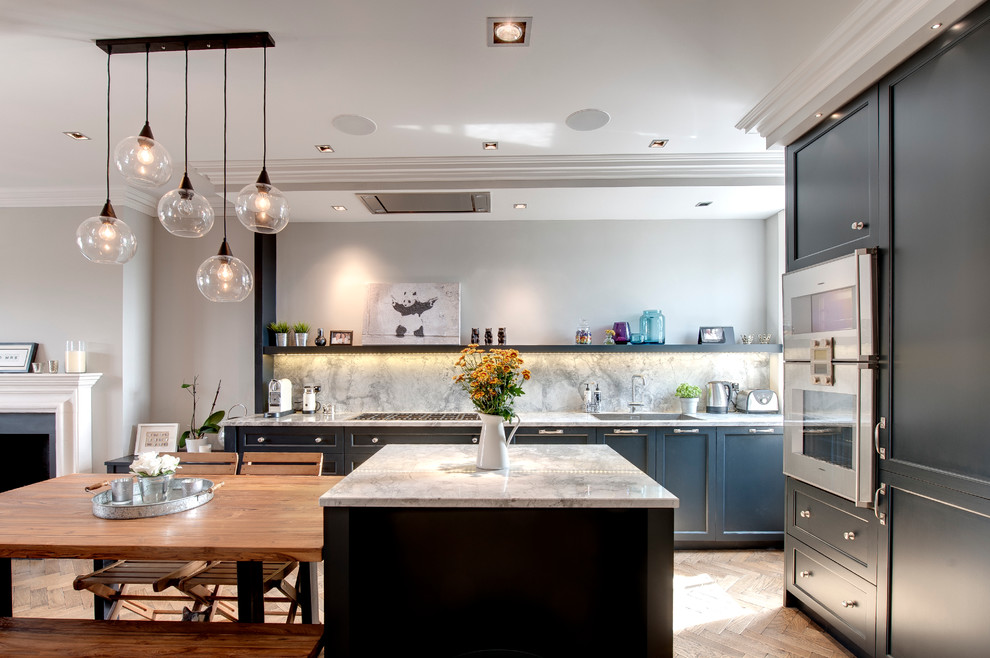 Mid-sized contemporary open plan kitchen in London with shaker cabinets, blue cabinets, with island, an undermount sink, granite benchtops, medium hardwood floors, stone slab splashback and panelled appliances.