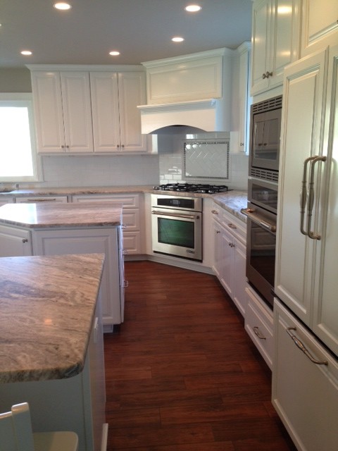 Large transitional medium tone wood floor eat-in kitchen photo in Seattle with raised-panel cabinets, white cabinets, white backsplash, subway tile backsplash and stainless steel appliances