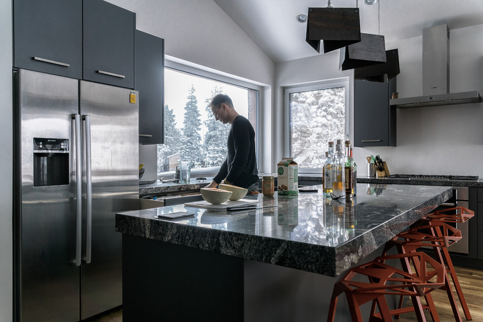 Kitchen - mid-sized modern l-shaped dark wood floor and brown floor kitchen idea in Denver with an undermount sink, flat-panel cabinets, gray cabinets, stainless steel appliances, an island and gray countertops