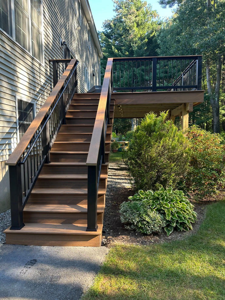 Large modern backyard and ground level deck in Boston with no cover and mixed railing.