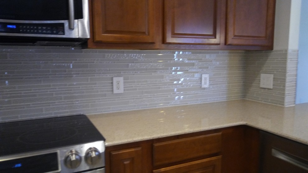 Eat-in kitchen - mid-sized transitional l-shaped eat-in kitchen idea with quartz countertops, white backsplash, glass tile backsplash and a peninsula