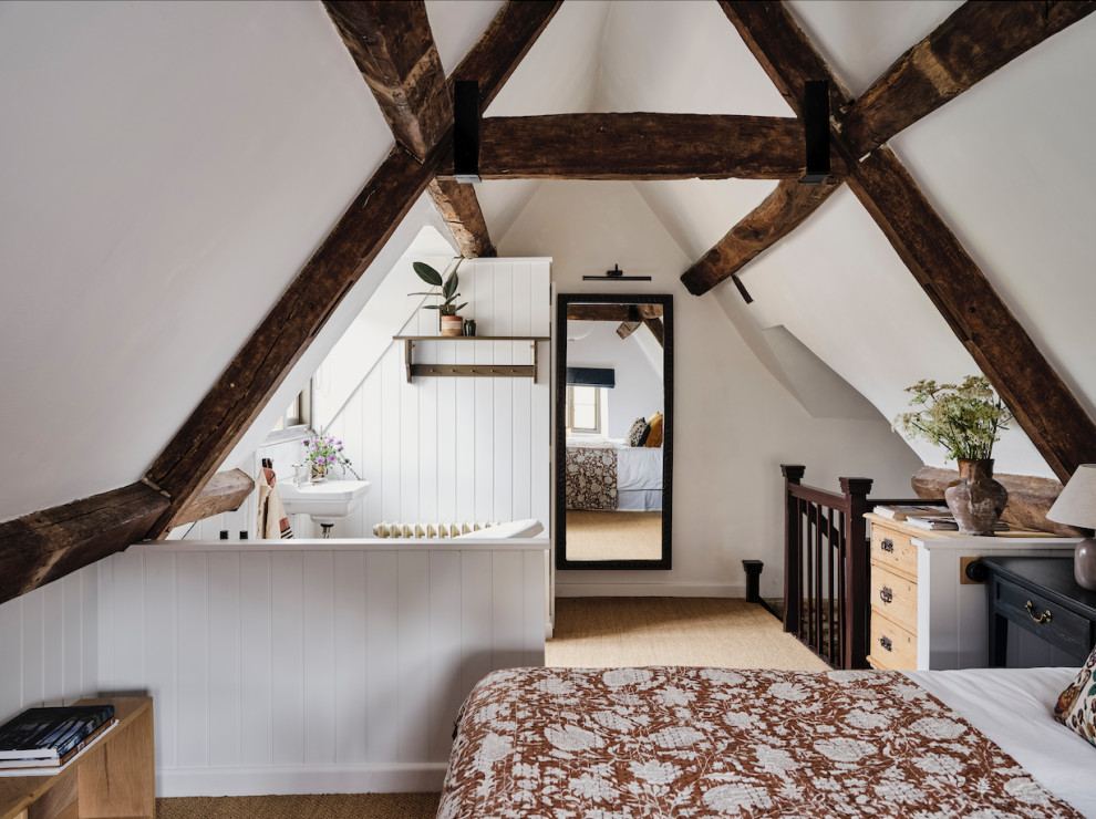 На фото: большая хозяйская спальня: освещение в стиле кантри с белыми стенами, ковровым покрытием, коричневым полом и балками на потолке с