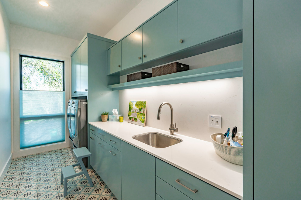 Design ideas for a large contemporary galley dedicated laundry room in Austin with an undermount sink, flat-panel cabinets, turquoise cabinets, quartzite benchtops, white walls, a side-by-side washer and dryer, turquoise floor and white benchtop.