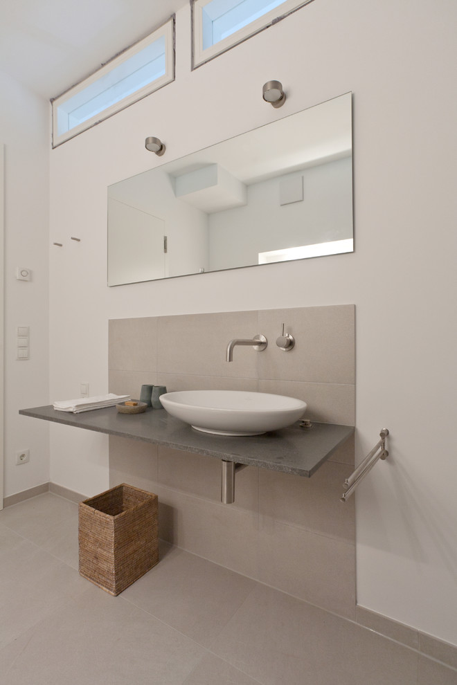 Inspiration for a mid-sized contemporary 3/4 bathroom in Berlin with gray tile, ceramic tile, white walls, a vessel sink, a curbless shower, a wall-mount toilet and pebble tile floors.