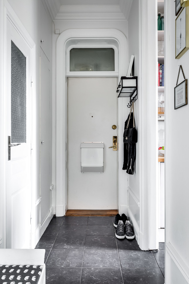 Photo of a small scandinavian hallway in Stockholm with white walls and grey floor.