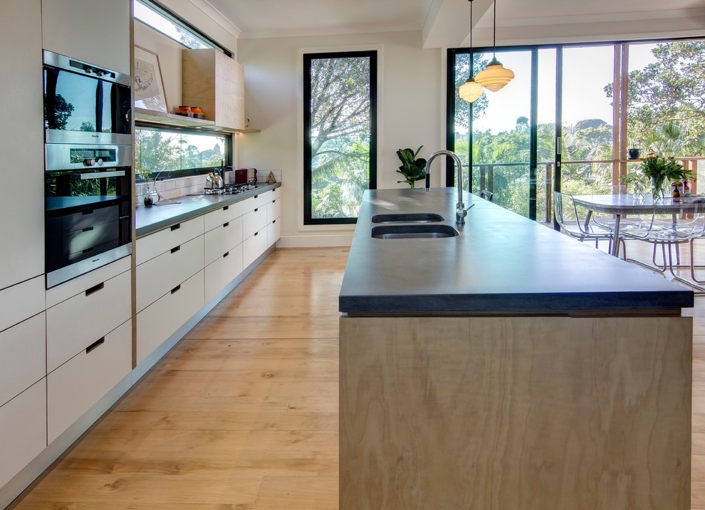 Photo of a mid-sized midcentury galley kitchen in Brisbane with light wood cabinets, concrete benchtops, white splashback, subway tile splashback, concrete floors and with island.