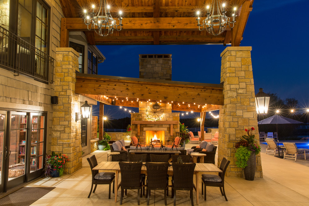 Large country backyard patio in Kansas City with a fire feature, concrete slab and an awning.
