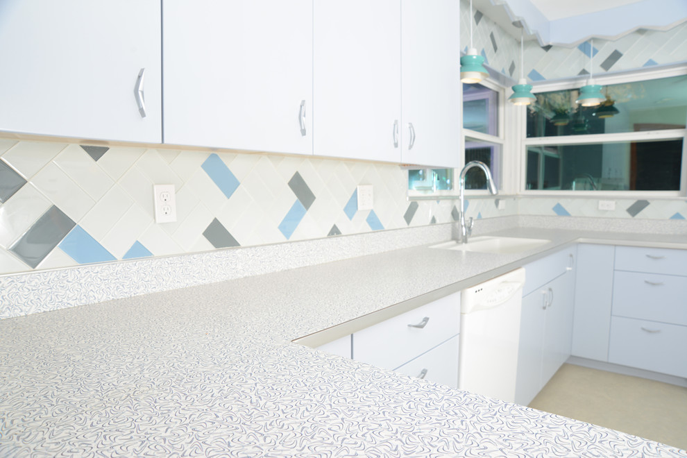 This is an example of a mid-sized midcentury u-shaped eat-in kitchen in Miami with an integrated sink, flat-panel cabinets, laminate benchtops, glass tile splashback, blue cabinets, beige splashback, linoleum floors, no island and beige floor.