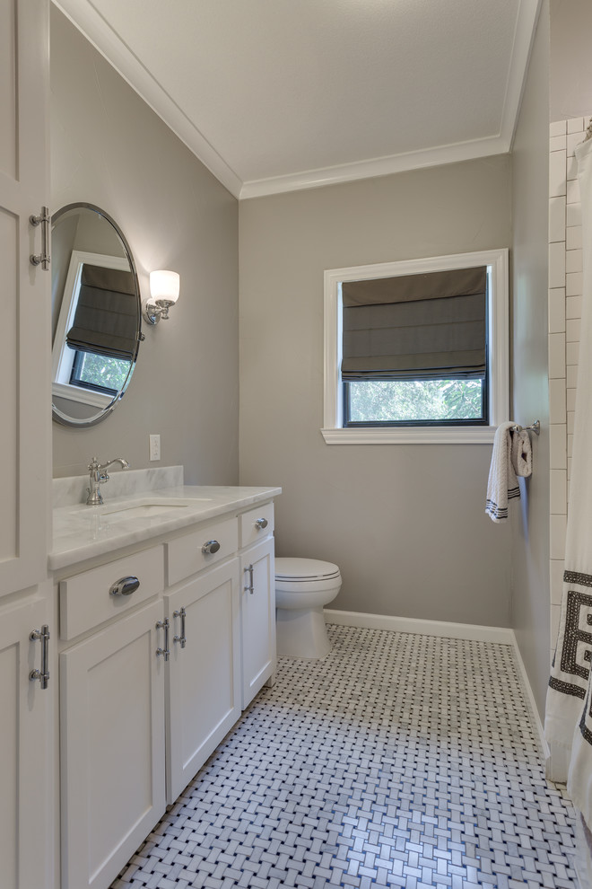Photo of a small country kids bathroom in Dallas with shaker cabinets, white cabinets, an alcove tub, a shower/bathtub combo, a one-piece toilet, white tile, subway tile, grey walls, mosaic tile floors, an undermount sink, marble benchtops, multi-coloured floor, a shower curtain and multi-coloured benchtops.