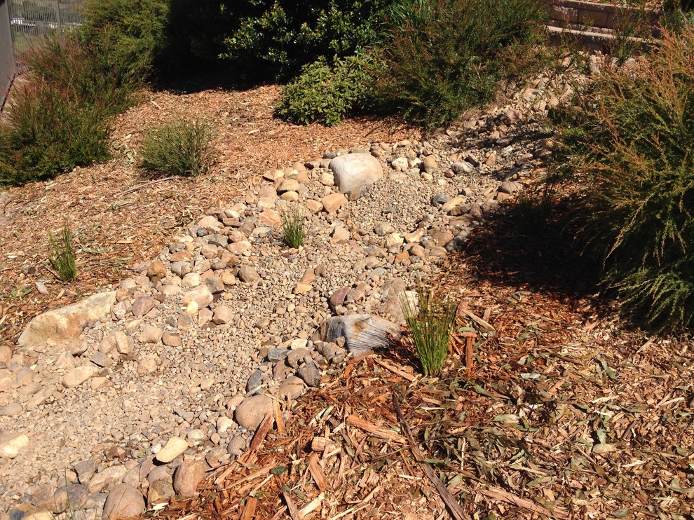 Photo of a mid-sized country sloped garden in Sunshine Coast with a water feature.