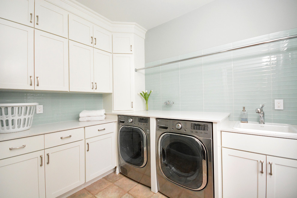 Photo of a mid-sized transitional l-shaped dedicated laundry room in New York with a drop-in sink, recessed-panel cabinets, white cabinets, marble benchtops, blue walls, terra-cotta floors and a side-by-side washer and dryer.