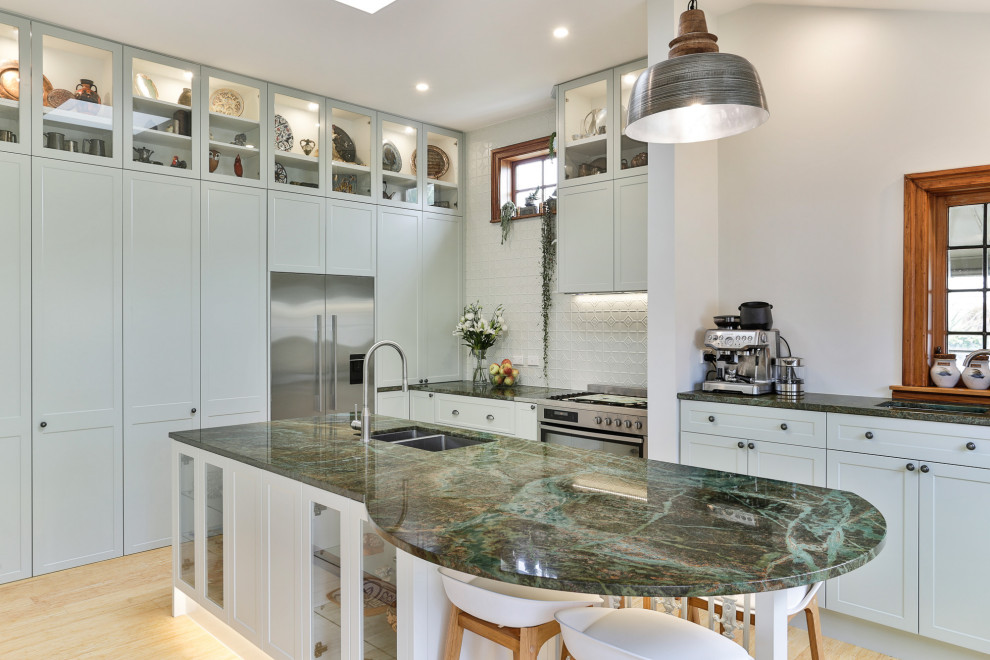 Inspiration for a large transitional l-shaped kitchen in Christchurch with an undermount sink, shaker cabinets, white cabinets, white splashback, stainless steel appliances, light hardwood floors, with island, beige floor and green benchtop.