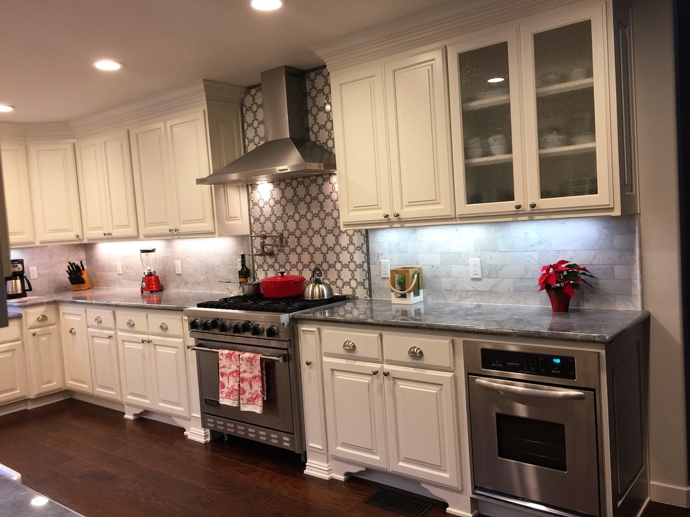Large transitional u-shaped dark wood floor kitchen photo in Orange County with a farmhouse sink, raised-panel cabinets, white cabinets, granite countertops, white backsplash, stone tile backsplash and no island