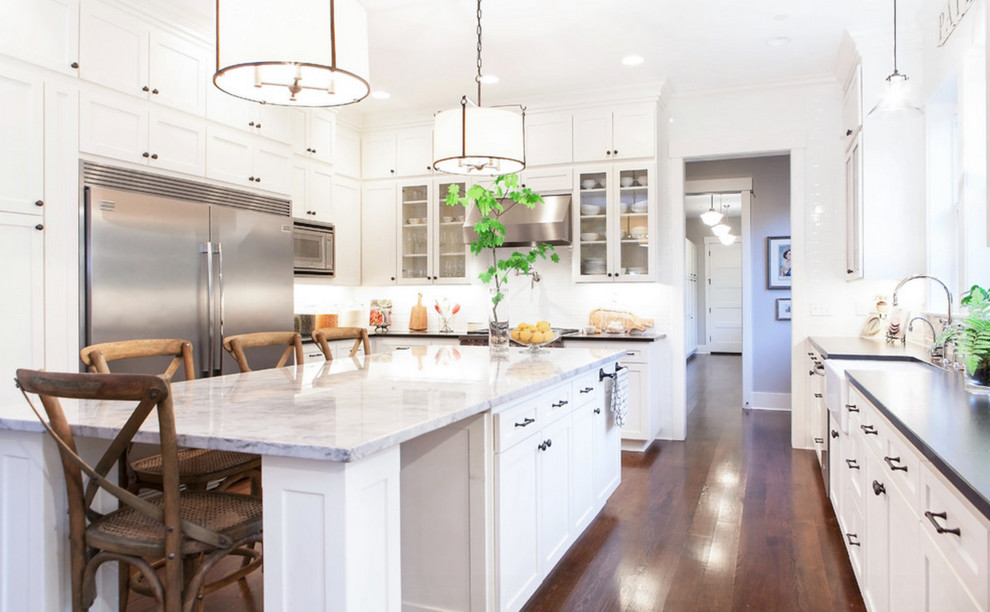 Traditional u-shaped kitchen in Portland with a farmhouse sink, recessed-panel cabinets, white cabinets, stainless steel appliances, dark hardwood floors and with island.