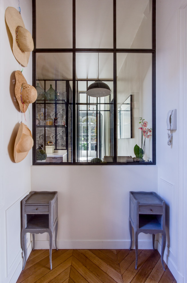 Photo of a mid-sized contemporary vestibule in Paris with white walls and medium hardwood floors.