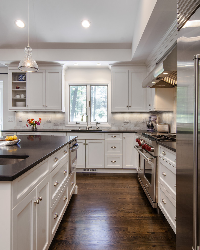 Example of a large transitional l-shaped dark wood floor eat-in kitchen design with white cabinets, granite countertops, white backsplash, stainless steel appliances, an island and shaker cabinets