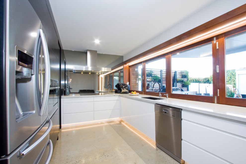 Large modern u-shaped eat-in kitchen in Brisbane with an undermount sink, white cabinets, quartzite benchtops, mirror splashback and white benchtop.