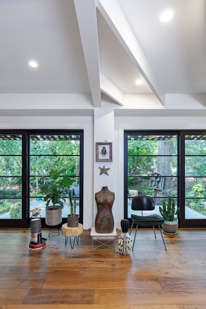 Esempio di un soggiorno contemporaneo di medie dimensioni e aperto con pareti bianche, pavimento in legno massello medio, pavimento marrone e travi a vista
