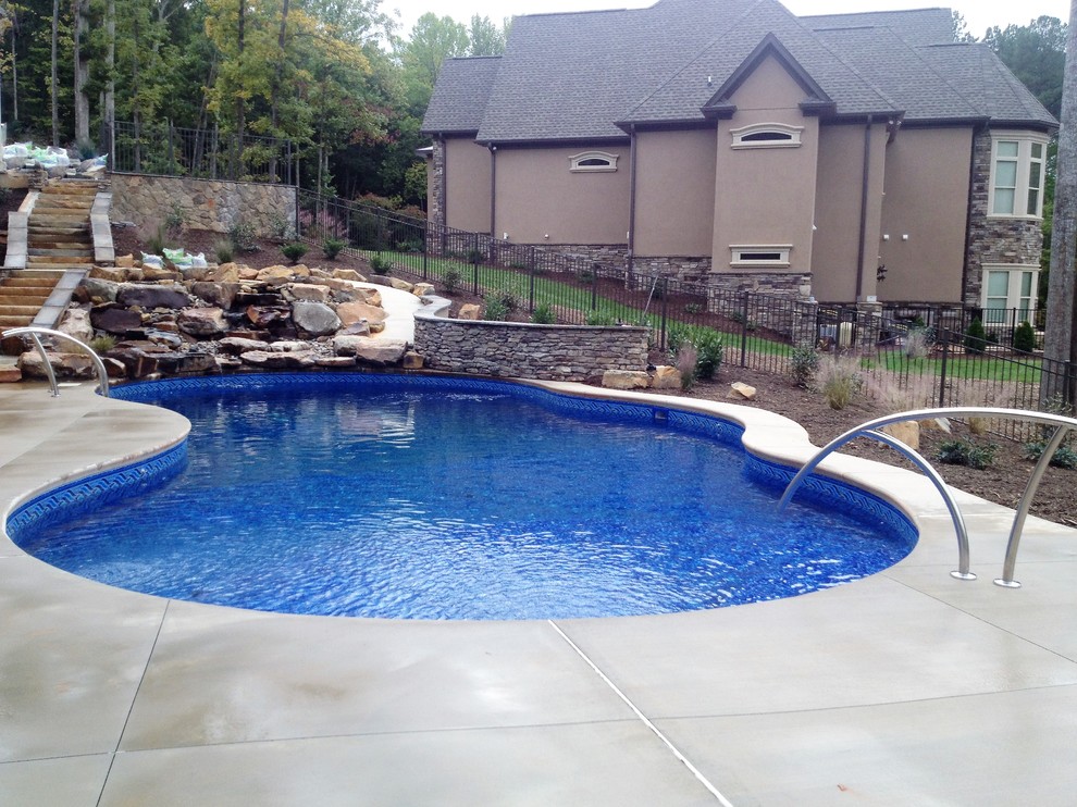 Large modern backyard custom-shaped natural pool in Other with a water feature.