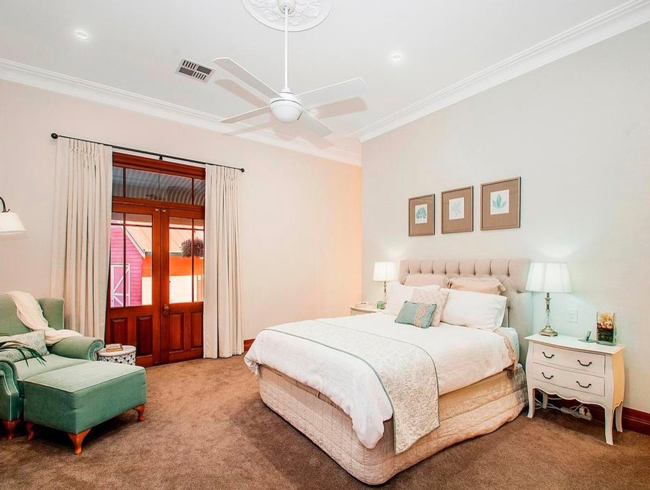 Expansive traditional master bedroom in Sydney with beige walls and carpet.