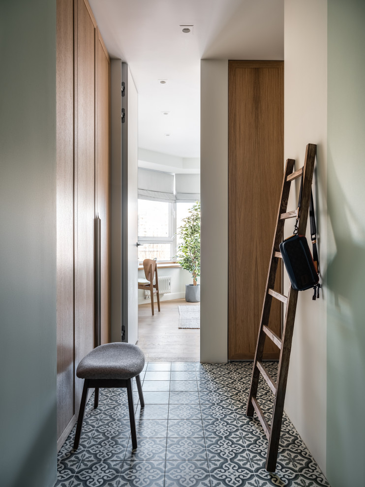 Cette image montre une entrée design avec un couloir, un mur vert, un sol en carrelage de porcelaine, une porte blanche et un sol vert.