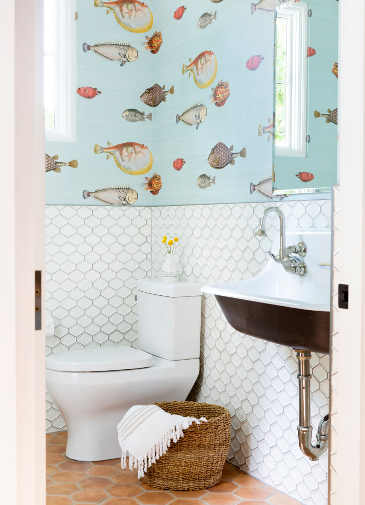 Modelo de cuarto de baño infantil y doble tradicional renovado con sanitario de dos piezas, baldosas y/o azulejos blancos, paredes multicolor, lavabo de seno grande, suelo marrón y papel pintado