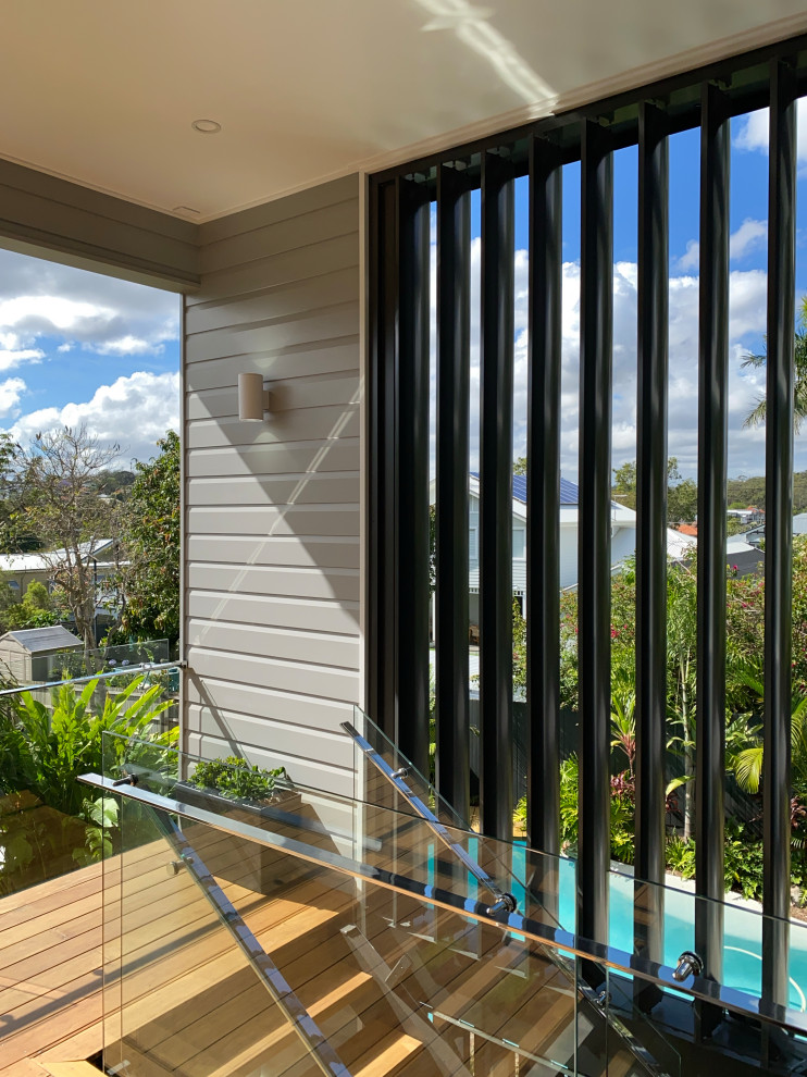 Photo of a large contemporary back first floor glass railing terrace in Brisbane with a roof extension.