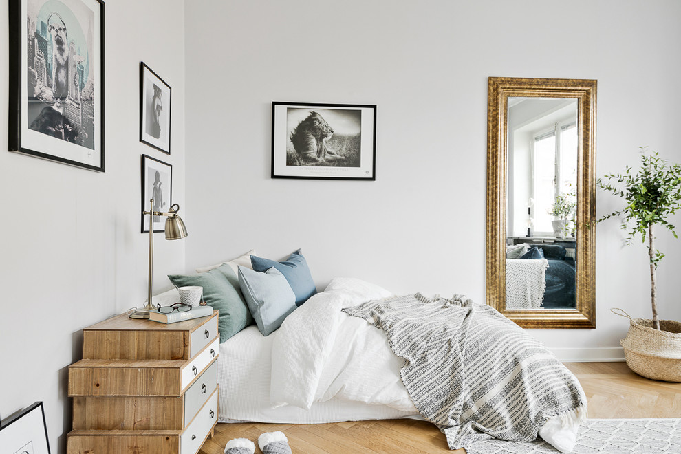 Skandinavisk inredning av ett sovrum, med vita väggar och mellanmörkt trägolv