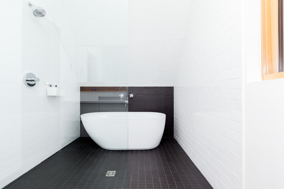 Design ideas for a contemporary master wet room bathroom in Edmonton with flat-panel cabinets, white cabinets, a freestanding tub, a two-piece toilet, white tile, ceramic tile, white walls, a vessel sink, solid surface benchtops, black floor and an open shower.