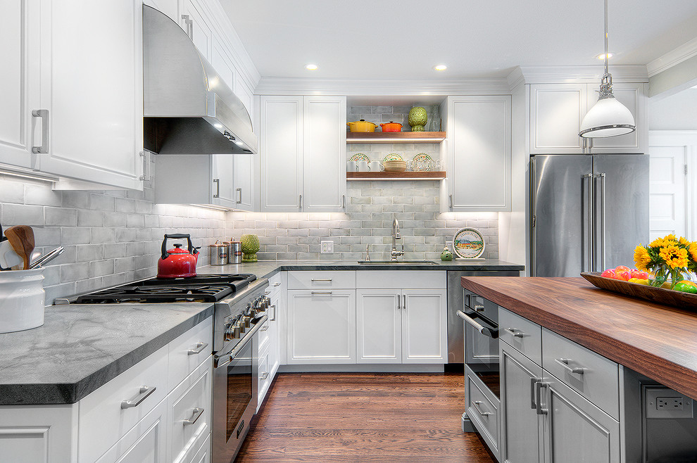 Photo of a mid-sized country l-shaped eat-in kitchen in San Francisco with an undermount sink, recessed-panel cabinets, white cabinets, granite benchtops, grey splashback, ceramic splashback, stainless steel appliances, medium hardwood floors and with island.