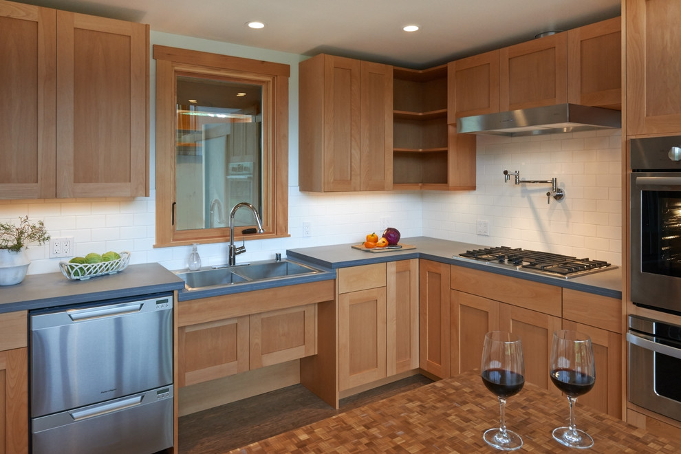 Mid-sized transitional l-shaped eat-in kitchen in Seattle with a double-bowl sink, shaker cabinets, light wood cabinets, solid surface benchtops, white splashback, subway tile splashback, stainless steel appliances, bamboo floors and with island.