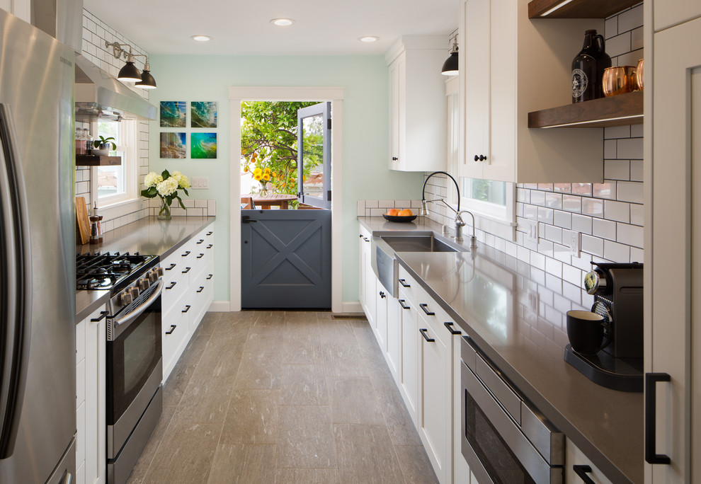 Photo of a mid-sized beach style galley eat-in kitchen in San Diego with a farmhouse sink, shaker cabinets, white cabinets, quartz benchtops, white splashback, subway tile splashback, stainless steel appliances, porcelain floors, no island, grey floor and purple benchtop.