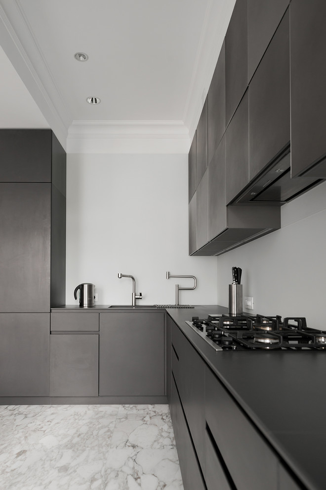 This is an example of a mid-sized contemporary l-shaped eat-in kitchen in Moscow with an undermount sink, flat-panel cabinets, black cabinets, glass sheet splashback, marble floors, no island and white splashback.