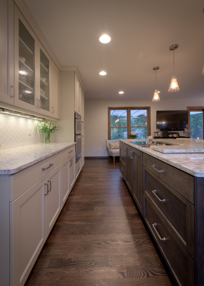 Kitchen - large transitional dark wood floor kitchen idea in Denver with an undermount sink, shaker cabinets, solid surface countertops, white backsplash, ceramic backsplash, stainless steel appliances and an island