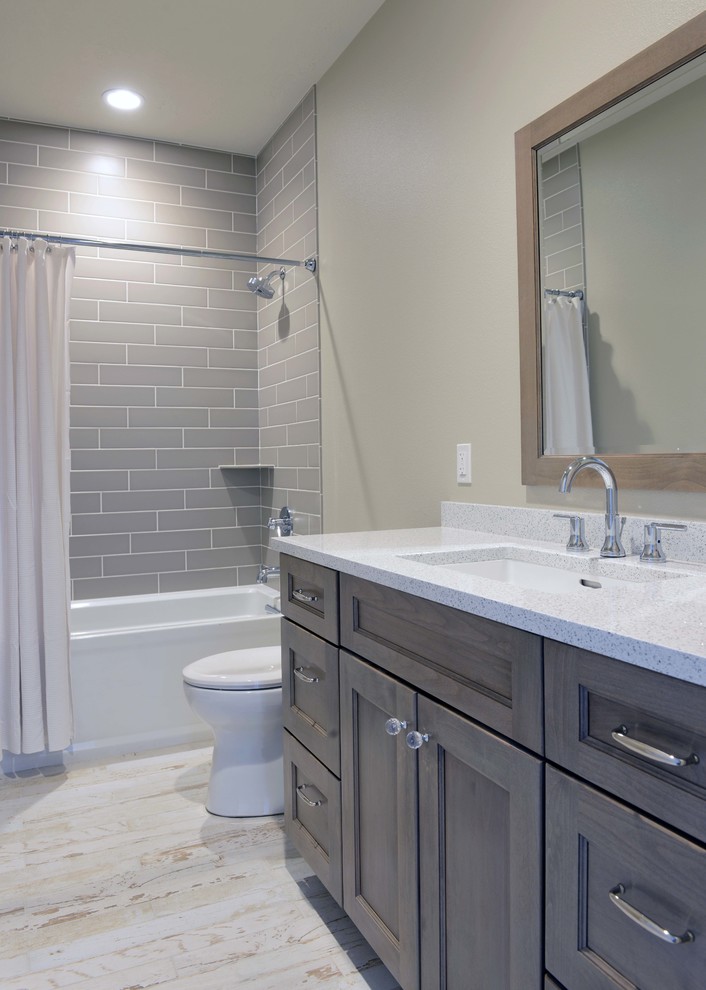 Inspiration for a mid-sized transitional bathroom in Other with an undermount sink, flat-panel cabinets, grey cabinets, engineered quartz benchtops, an alcove tub, a shower/bathtub combo, a two-piece toilet, gray tile, subway tile, beige walls, light hardwood floors, white floor and a shower curtain.